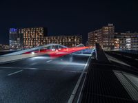 a train on an elevated track passing through a city at night, with buildings and cars