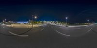 an empty street with a stop sign in the middle of it at night with several buildings behind