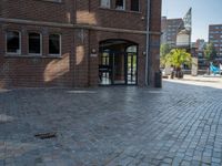 an entrance to a brick building with the clock tower in the background, taken from behind