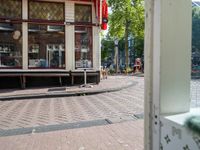 a bike parked in the street near some shops and parked bikes behind a glass door