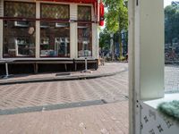 a bike parked in the street near some shops and parked bikes behind a glass door