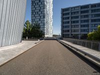 a long walkway runs near some buildings, a parking lot and the city beyond it