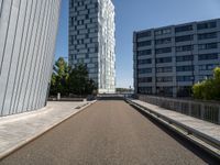 a long walkway runs near some buildings, a parking lot and the city beyond it