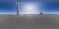 a solar cell phone camera view of an intersection with wind turbines and water in the background