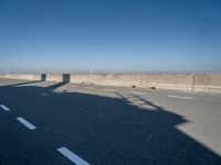 the shadow of a person on a skateboard on a highway with a sign in the distance