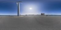 an empty road with a wind turbine in the foreground and blue sky above it