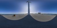 a fish eye lens reflecting the view of a wind turbine at the edge of the road