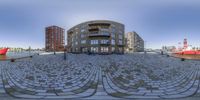 fisheye view of a round building on the waterfront with other buildings in the background