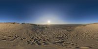 sun shining over the sand dunes and a clear blue sky above them is in front of an ocean