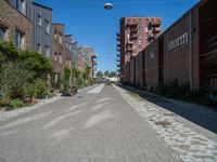 the empty street has bricks, brick planters and red brick buildings in the back