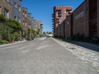 the empty street has bricks, brick planters and red brick buildings in the back