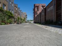 the empty street has bricks, brick planters and red brick buildings in the back