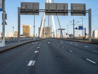 an empty road that is almost empty during the day with buildings and light poles in the background