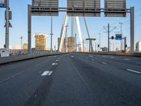 an empty road that is almost empty during the day with buildings and light poles in the background