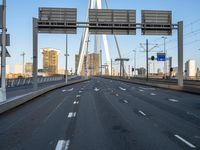 an empty road that is almost empty during the day with buildings and light poles in the background