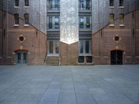 a very big building with an interesting looking window, near some stairs and a brick wall