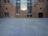 a very big building with an interesting looking window, near some stairs and a brick wall