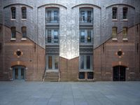 a very big building with an interesting looking window, near some stairs and a brick wall