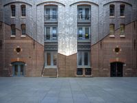 a very big building with an interesting looking window, near some stairs and a brick wall