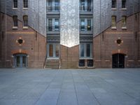 a very big building with an interesting looking window, near some stairs and a brick wall