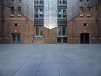 a very big building with an interesting looking window, near some stairs and a brick wall