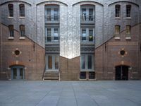 a very big building with an interesting looking window, near some stairs and a brick wall