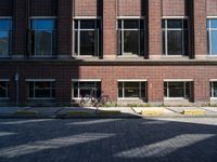 a bicycle sits in the middle of a brick parking space outside of a brick building