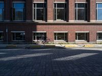 a bicycle sits in the middle of a brick parking space outside of a brick building