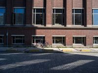 a bicycle sits in the middle of a brick parking space outside of a brick building