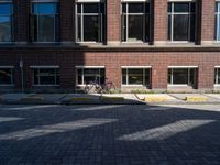 a bicycle sits in the middle of a brick parking space outside of a brick building