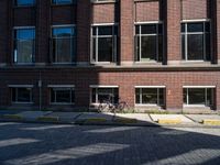 a bicycle sits in the middle of a brick parking space outside of a brick building