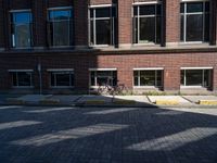 a bicycle sits in the middle of a brick parking space outside of a brick building