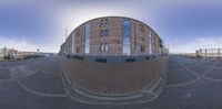 a fish eye lens picture of a building by the water with a train in the background