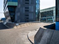 a skateboarder in action on the edge of a concrete ramp near buildings and a street