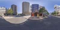 a wide angle panorama of a street in the middle of a large city with buildings and people