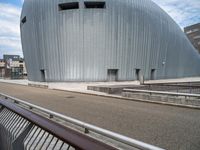 the building has a big oval shaped entrance with metal bars on it, and a bench in front