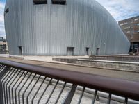 the building has a big oval shaped entrance with metal bars on it, and a bench in front