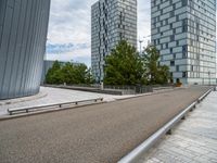 a bench and railing near some tall buildings on a cloudy day / photograph credit j kro