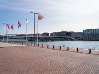 a building is visible behind the flags at the water's edge and the walkway next to it