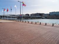 a building is visible behind the flags at the water's edge and the walkway next to it