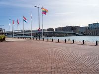 a building is visible behind the flags at the water's edge and the walkway next to it