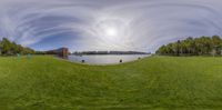 a fisheye lens is shown, looking down at a wide open field with a lake in the background