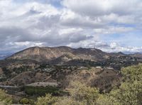 the hollywood sign sits on the top of a mountain overlooking an urban city in the distance