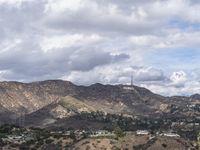 the hollywood sign sits on the top of a mountain overlooking an urban city in the distance