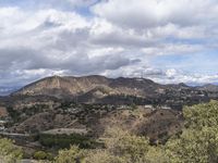 the hollywood sign sits on the top of a mountain overlooking an urban city in the distance