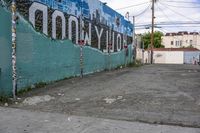 a street corner with a mural in the back, a sign that says hollywood on the side, and a stop sign on the sidewalk