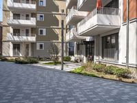 empty walkway between two beige building with parking spaces in front of them and trees on either side