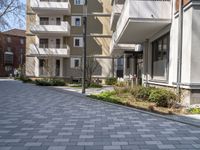 empty walkway between two beige building with parking spaces in front of them and trees on either side