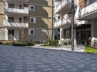 empty walkway between two beige building with parking spaces in front of them and trees on either side