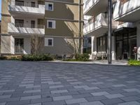 empty walkway between two beige building with parking spaces in front of them and trees on either side